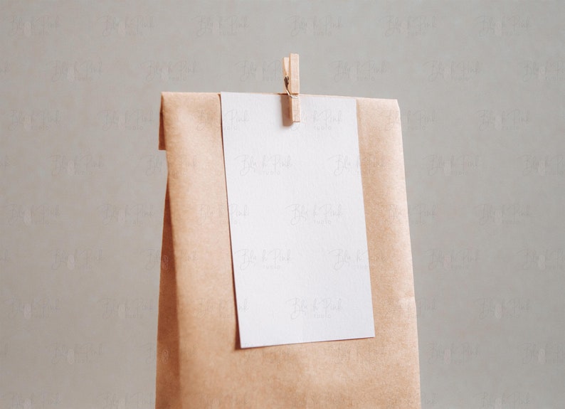 Puede incluir: Una bolsa de papel marr&oacute;n con una tarjeta blanca unida a ella con una pinza de madera. La tarjeta est&aacute; en blanco.
