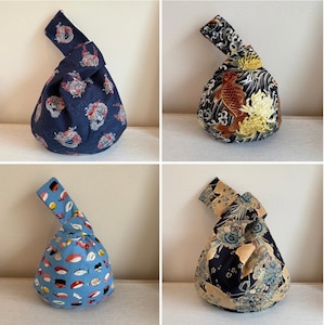 Puede incluir: Cuatro bolsas de nudo japonesas con diversos patrones. Las bolsas presentan diseños como carpas koi, sushi y motivos florales. Las bolsas son en tonos azules, negros y dorados, con un asa anudada en la parte superior.