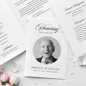 May include: Black and white funeral program with a photo of a man smiling. The program includes the order of service, obituary, and funeral arrangements. The text "Honoring The Life Of" is written in a decorative script font. The text "Arnold Reynolds" is printed below the photo. The dates "April 12, 1930 - May 20, 2020" are printed below the name.