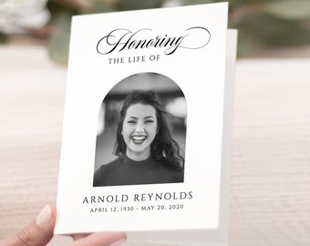 May include: A black and white photo memorial card with an arched frame. The card features a photo of a woman smiling. The text reads "Honoring the Life of Arnold Reynolds April 12, 1930 - May 20, 2020".