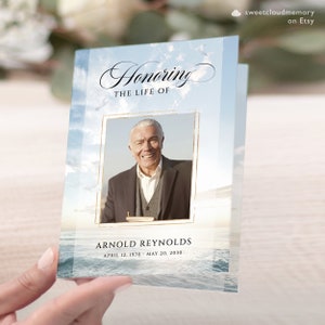 May include: A blue and white memorial card with a photo of a man in a suit and tie. The card has the text "Honoring the Life of Arnold Reynolds April 12, 1970 - May 20, 2030".