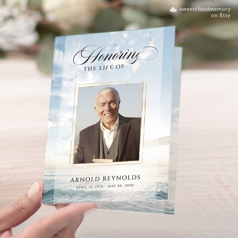 May include: A blue and white memorial card with a photo of a man in a suit and tie. The card has the text "Honoring the Life of Arnold Reynolds April 12, 1970 - May 20, 2030".