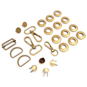 May include: A set of gold-toned metal hardware for crafting bags and other accessories. The set includes D-rings, swivel clasps, eyelets, and studs.