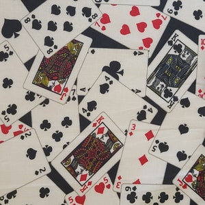 May include: A fabric pattern featuring playing cards scattered across a black background. The cards display various suits, including spades, hearts, clubs, and diamonds. The cards are in various orientations, with some face up and others partially visible.