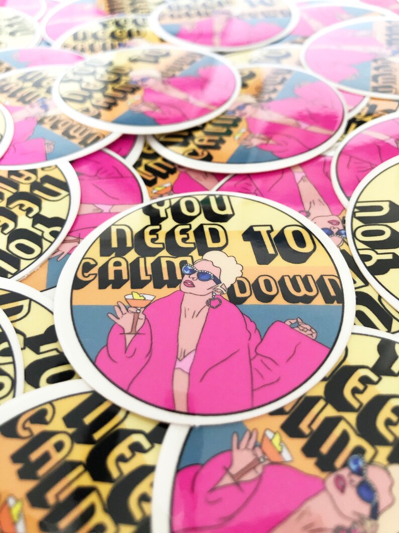 May include: A stack of round stickers with a yellow background and a woman in a pink robe holding a cocktail. The text on the sticker reads "You Need To Calm Down".