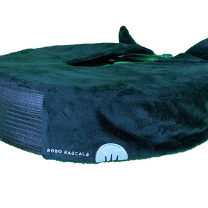 May include: A dark blue plush pet bed with a black mesh base and the text "ROBO RASCALS" on the side. The bed has two small ears on top.