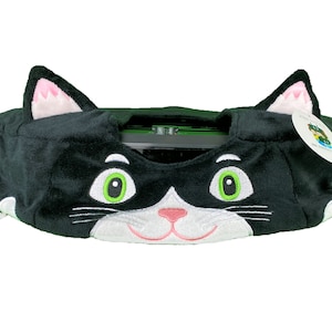 May include: Black and white plush cat-shaped cover for a Roomba vacuum cleaner. The cover has green eyes, a pink nose, and white whiskers.