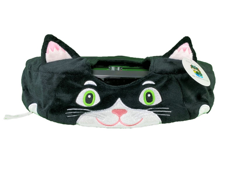 May include: Black and white plush cat-shaped cover for a Roomba vacuum cleaner. The cover has green eyes, a pink nose, and white whiskers.