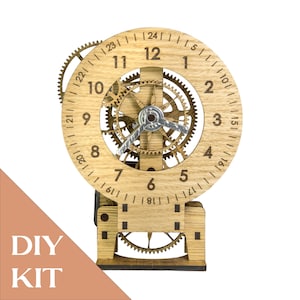 Peut inclure: Une horloge en kit DIY en bois brun clair avec un cadran circulaire gravé des chiffres 1 à 24 sur le pourtour. L'horloge présente des engrenages internes apparents, un mécanisme d'aiguilles central argenté et un support de base robuste.