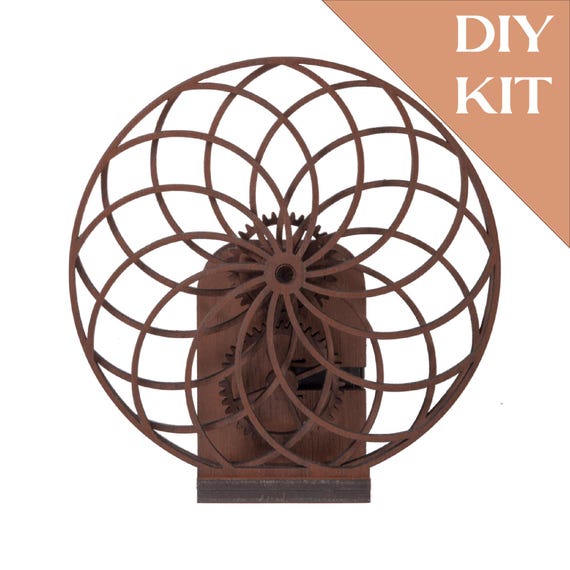 A laser-cut walnut wood spirograph that you assemble yourself into a living, spinning desk sculpture — the build IS the experience.