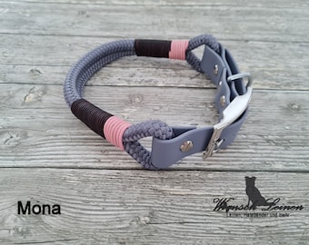May include: A gray, pink, and brown rope dog collar with a silver buckle. The collar is on a wooden surface. The text "Mona" is visible in the lower left corner of the image.