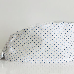 May include: White surgical scrub cap with a blue and white pattern of small teardrop shapes.