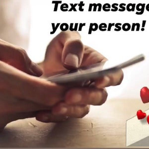 May include: A person's hands holding a smartphone with the text "Text message from your person!" above the phone. A white envelope with three red hearts floating above it.