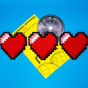 May include: Three red pixelated heart-shaped patches with white outlines. The patches are arranged in a row, with the middle patch slightly higher than the other two. The patches are on a yellow background with a black and white circle in the background.