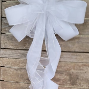 May include: A white bow with a sheer, layered ribbon. The bow is tied with a long tail and is perfect for adding a touch of elegance to any occasion.