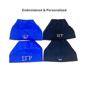 May include: Four fleece beanies, two blue and two black, with embroidered gold lettering that reads "ΣΓΡ 1922".