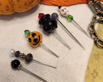 Halloween Pins With a Glass witches pot with red flame and Pumpkin and Skull and purple bead pins.