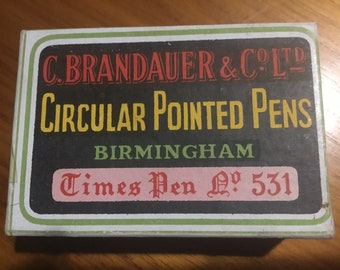Könnte beinhalten: Eine Vintage-Schachtel mit C. Brandauer & Co. Ltd. Circular Pointed Pens aus Birmingham, England. Die Schachtel ist grün, schwarz und rot mit dem Text "Times Pen No. 531" auf der Vorderseite.