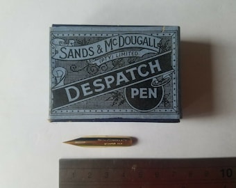 Könnte beinhalten: Eine blaue Schachtel mit dem Text "SANDS & MCDOUGALLE (PTY) LIMITED. DESPATCH PEN" darauf. Neben der Schachtel liegt eine goldene Feder.
