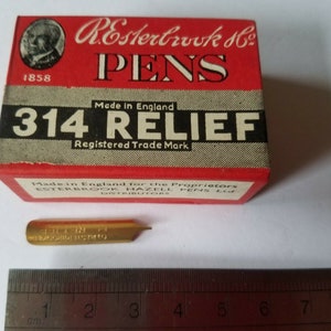 May include: A red box with white lettering that reads "R. Esterbrook & Co. Pens 314 RELIEF Registered Trade Mark" and a gold-colored pen nib with the text "314 RELIEF" on it. The box is made in England for the proprietors Esterbrook Hazell Pens Ltd. Distributors.