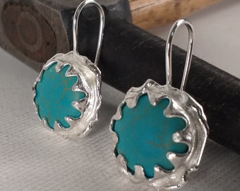 May include: A pair of silver dangle earrings with turquoise stones set in a textured, scalloped design.
