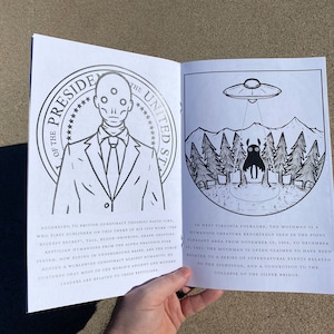 May include: An open book with black and white illustrations. The left page features a man in a suit with three eyes and the text "President of the United States". The right page features a black creature with large eyes and a flying saucer above it. The text reads "In West Virginia folklore, the Mothman is a humanoid creature reportedly seen in the Point Pleasant area from November 15, 1966, to December 15, 1967. The Mothman is often claimed to have been related to a series of supernatural events related to the sightings, and a connection to the collapse of the Silver Bridge."