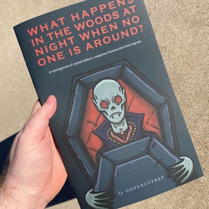 May include: A coloring book titled "What Happens in the Woods at Night When No One is Around?" with a dark blue cover featuring an illustration of a vampire sitting in a coffin. The book is a coloring book of cryptid, folklore, conspiracy theories and urban legends by GOPENCYPREP.