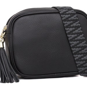 May include: A black leather crossbody bag with a gold chain and tassel. The bag has a patterned strap and a rectangular shape.