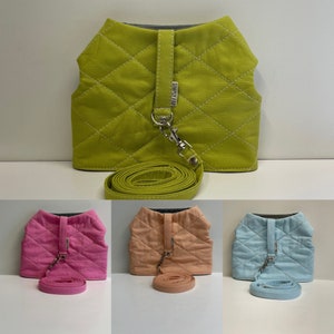 May include: Three quilted dog harnesses with matching leashes in lime green, pink, and light blue. The harnesses have a silver buckle and a label that says "Simply Fab".