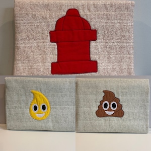 May include: Two grey fabric panels with embroidered images. The left panel has a yellow teardrop with a smiling face. The right panel has a brown poop emoji with a smiling face.