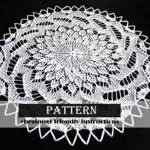 Op de afbeelding: Wit gehaakt tafellaken met een delicaat, ingewikkeld patroon. Het tafellaken is rond met een middelpunt en een gegolfde rand. De tekst "PATTERN + beginner friendly instructions" wordt onder het tafellaken weergegeven.