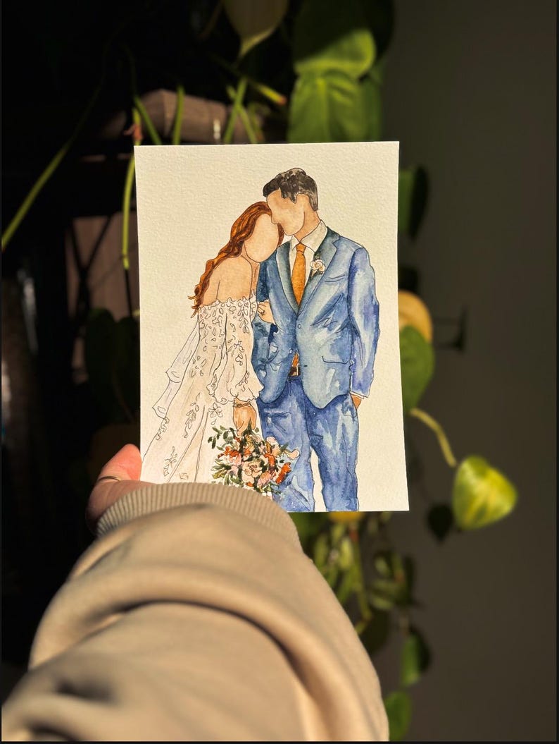 May include: Watercolor painting of a couple in wedding attire. The bride is wearing a white dress with lace detailing and the groom is wearing a blue suit with a light orange tie. They are standing close together and the bride is holding a bouquet of flowers.