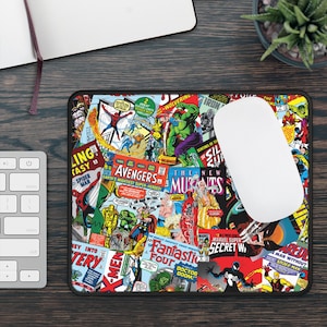 Könnte beinhalten: Ein rechteckiges Mauspad mit einer Collage aus farbenfrohen Comic-Covern mit verschiedenen Superhelden. Eine weiße Computermaus liegt auf dem Mauspad, neben einer Tastatur und einem Notizbuch.