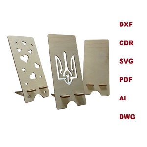 May include: Three light-colored wooden phone stands with cut-out designs, including one with heart shapes and one with a trident symbol. The text DXF, CDR, SVG, PDF, AI, and DWG is displayed in red on the right side of the wooden stands.