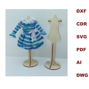 May include: A blue and green striped crocheted dress with white lace trim on a wooden doll stand. The dress has a ruffled hem and long sleeves. The stand is made of wood and has a round base.