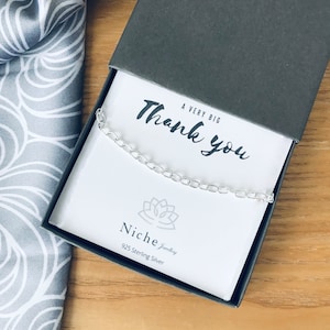 May include: A silver chain necklace in a gray box with a white card that says "A Very Big Thank You" and "Niche Jewelry 925 Sterling Silver".