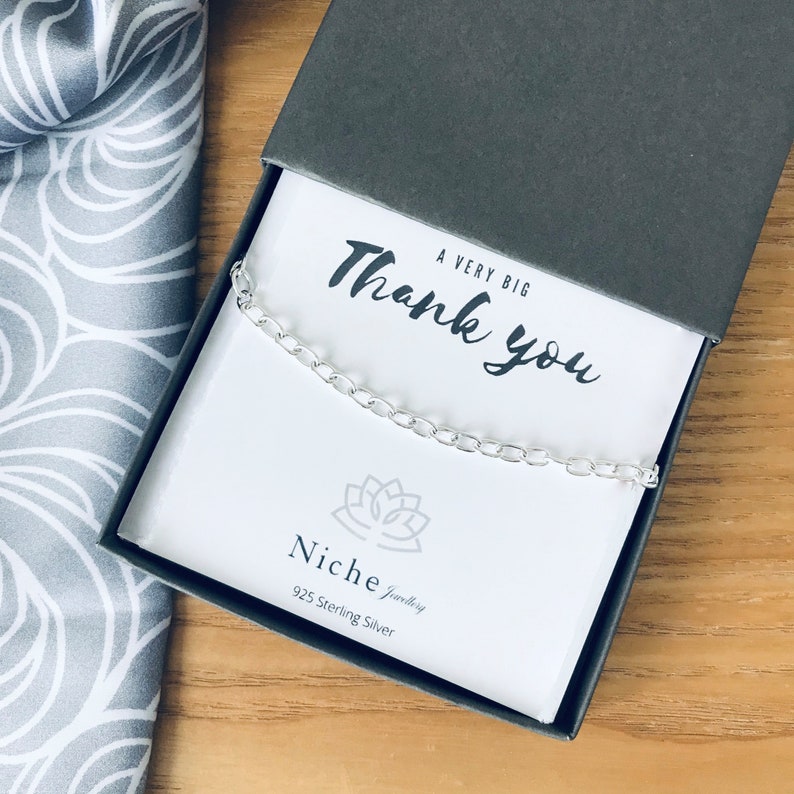 May include: A silver chain necklace in a gray box with a white card that says "A Very Big Thank You" and "Niche Jewelry 925 Sterling Silver".