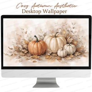 May include: A computer monitor displaying a digital wallpaper featuring a watercolour illustration of four pumpkins in shades of orange and cream surrounded by dried autumn leaves. The text Cozy Autumn Aesthetic Desktop Wallpaper is above.