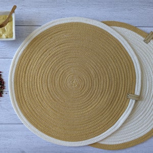 Peut inclure: Deux sets de table ronds avec un bord extérieur blanc et un centre beige. Les sets de table sont en corde tressée et ont une texture subtile.