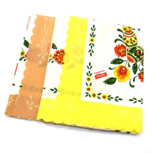 May include: Two yellow and brown fabric tablecloths with a scalloped edge and a floral pattern. The tablecloth on the right has the text "Produkt Polski" in red.