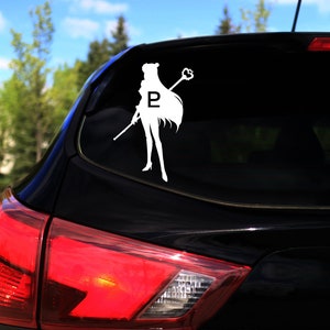 Op de afbeelding: Een zwarte auto met een witte vinyl sticker van een vrouwelijke figuur die een staf vasthoudt met een hartvormige bovenkant. De figuur heeft een ster op haar borst en de letter "P" op haar borst.