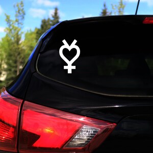 Op de afbeelding: Een zwarte auto met een witte vinyl sticker van een hart in een symbool op de achterruit.