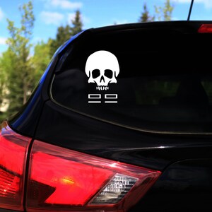 May include: A black car with a white skull and crossbones sticker on the back window.