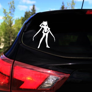 Op de afbeelding: Een witte vinyl sticker van een silhouet van een vrouwelijk anime-personage met lang haar en een rok. De sticker zit op de achterruit van een zwarte auto.