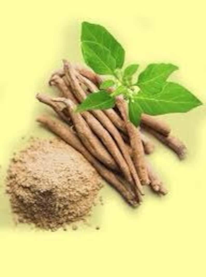 May include: A pile of tan-colored ashwagandha roots with a small pile of ashwagandha powder and a sprig of green leaves. The items are arranged on a light yellow background.