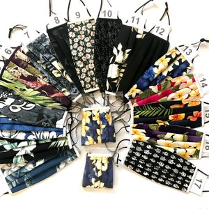 May include: A collection of 17 colorful face masks with various tropical and floral patterns. The masks are numbered 1 through 17 and are arranged in a fan shape.