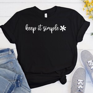 May include: Black t-shirt with white text that reads "keep it simple" and a white flower graphic.