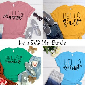 May include: Four t-shirts with different seasonal greetings. The shirts are pink, yellow, green, and blue. The text on the shirts reads "Hello Summer", "Hello Fall", "Hello Winter", and "Hello Spring".