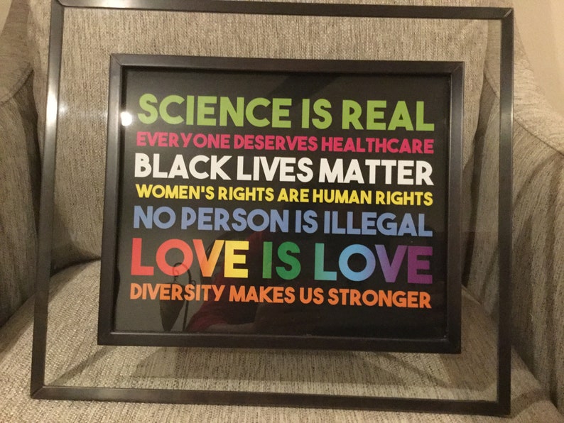 May include: Framed print with a black background and colourful text that reads "Science is real", "Everyone deserves healthcare", "Black lives matter", "Women's rights are human rights", "No person is illegal", "Love is love", and "Diversity makes us stronger".