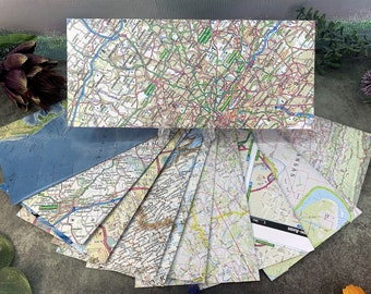 May include: A collection of vintage paper maps, some folded and some flat, with various locations and scales. The maps are in shades of blue, green, brown, and white, with black lines and text.